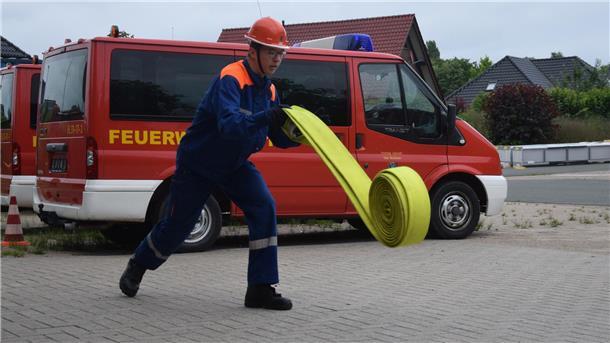 Paul Engling, Mitglied der Feuerwehr Nordenham, rollt einen Schlauch aus. 