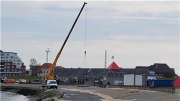 Ein Kran bringt Pavillons in der Grimmershörnbucht in Cuxhaven an ihre Plätze. Bald beginnt die Badesaison, die Strände öffnen.