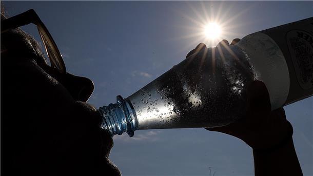 Eine Frau trinkt in der Sonne Mineralwasser.