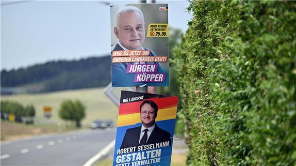 Plakate von AfD-Kandidat Robert Sesselmann CDU-Kandidat Jürgen Köpper hängen an einer Straße.