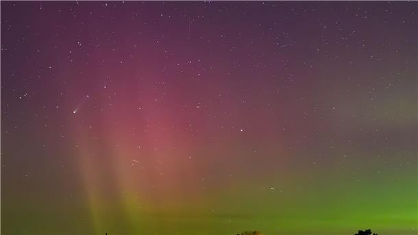 Bilder des Tages Polarlichter und der Komet Lemmon „C/2025 A6“ (Bildmitte links) leuchten am Nachthimmel über der Landschaft im östlichen Brandenburg.
