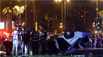Polizei und der Rettungsdienst stehen nahe des Strands von Tel Aviv neben dem Auto, das sich überschlagen hat.
