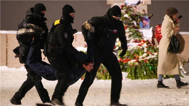 Polizeibeamte halten einen Mann fest, der Blumen zu Ehren von Alexej Nawalny an einem Denkmal für die Opfer der sowjetischen Unterdrückung in St. Petersburg niedergelegt hat.