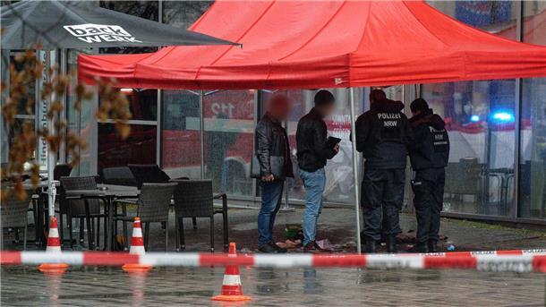 Schüsse in Fußgängerzone - Polizei stoppt bewaffneten Mann Polizeibeamte untersuchen unter einem Zeltdach den Tatort in Gummersbach.