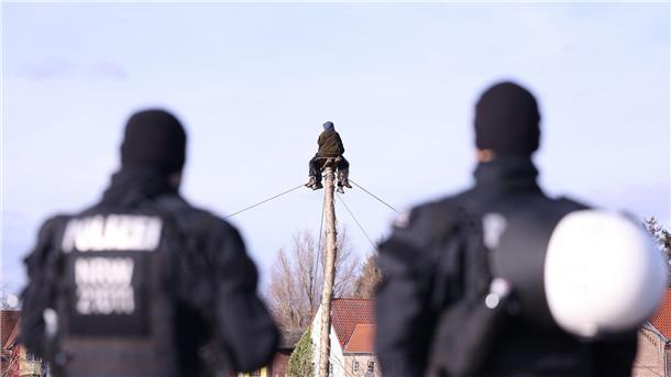 Lützerath: Aktivisten errichten neue Barrikaden Polizisten beobachten zwei Klimaschutzaktivisten die auf einem Monopod am Rand des Braunkohledorfes Lützerath sitzen.