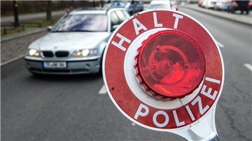 Polizisten kontrollieren auf einer Straße Autos.