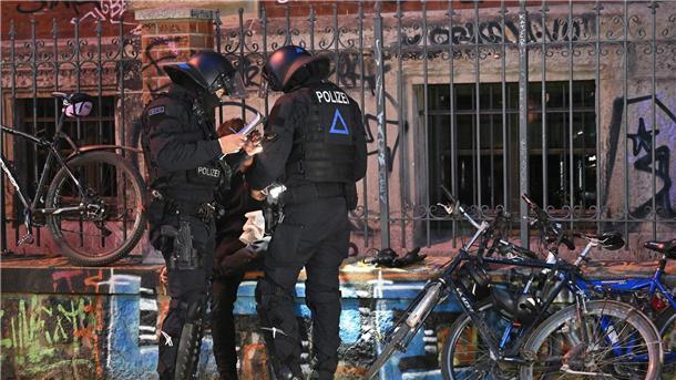 Polizisten nehmen die Personalien einer Person auf.