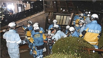 Polizisten retten im japanischen Suzu eine Frau aus einem eingestürzten Haus.