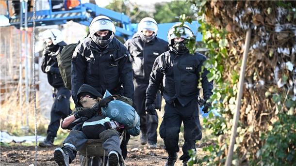 Lützerath bis auf zwei Aktivisten im Tunnel geräumt Polizisten schieben einen Klimaaktivisten mit einer Schubkarre aus Lützerath.