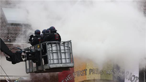 Abrissbagger in Lützerath - Widerstand bröckelt Polizisten stehen am zweiten Tag der Räumung im von Klimaaktivisten besetzten Braunkohleort Lützerath auf einer Hebebühne im Rauch von Pyrotechnik.
