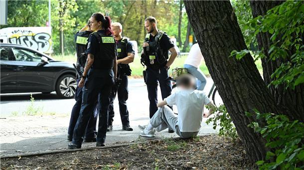 Auto fährt in Berlin in Kindergruppe - Fahrer festgenommen Polizisten stehen an der Unfallstelle.