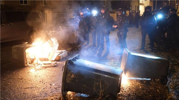 Rechte Kundgebung trifft auf starken Gegenprotest in Leipzig Polizisten stehen bei einer Demo an brennenden Müllcontainern.