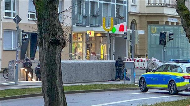 Polizisten stehen in Spezialausrüstung vor der Apotheke.