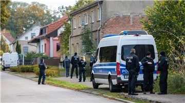 Polizisten stehen vor einem Grundstück in Tauche.