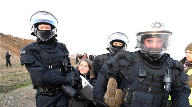 Polizisten tragen die schwedische Klimaaktivistin Greta Thunberg aus einer Gruppe von Demonstranten und Aktivisten heraus vom Rand des Braunkohlentagebaus Garzweiler II weg.
