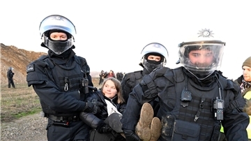 Polizisten tragen die schwedische Klimaaktivistin Greta Thunberg aus einer Gruppe von Demonstranten und Aktivisten heraus vom Rand des Braunkohlentagebaus Garzweiler II weg.