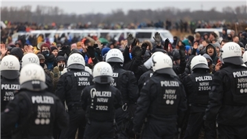 Polizisten und Demonstranten stehen sich bei der Demonstration von Klimaaktivisten am Rande des Braunkohletagebaus bei Lützerath gegenüber.