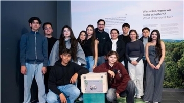 Eine Gruppe Menschen steht vor einer Foto-Wand.