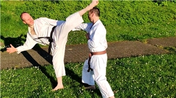 Zwei Männer in weißen Sportanzügen kämpfen auf einem Rasen miteinander