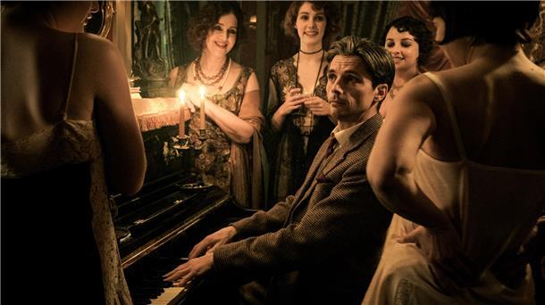Ein Mann am Klavier, umgeben von Frauen.