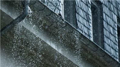 Regenwasser fließt während eines Unwetters an einer überfüllten Regenrinne hinunter.