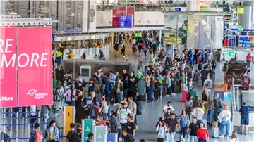 Reisende stehen am Flughafen Frankfurt Main  beim Einchecken in einer langen Schlange.