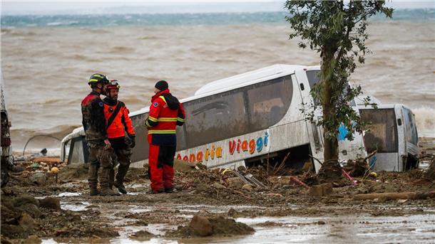 Rettungskräfte auf Ischia neben einem Bus, der durch schwere Regenfälle weggeschwemmt wurde.