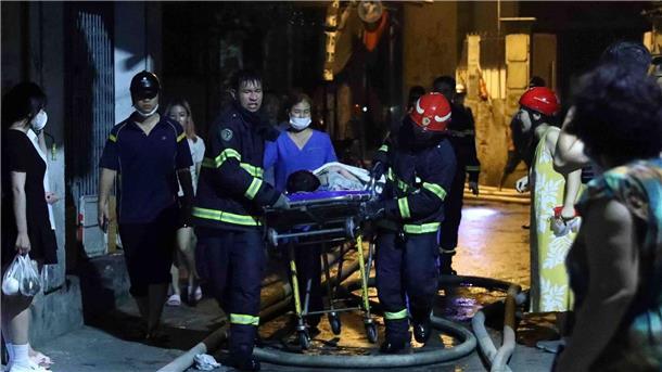 Opferzahl bei Brandkatastrophe in Wohnhaus steigt auf 56  Rettungskräfte tragen eine Person aus dem brennenden Gebäude in Hanoi.