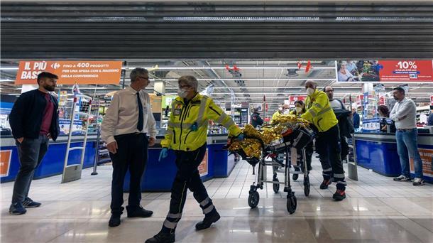 Rettungskräfte transportieren eine verletzte Person aus dem Supermarkt.