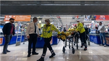 Rettungskräfte transportieren eine verletzte Person aus dem Supermarkt.