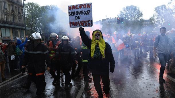 Frankreich: Ausschreitungen bei Protesten gegen Rentenreform Rettungskräfte und ein Demonstrant mit einem Plakat mit der Aufschrift „Macron, Räuber der Armen“ marschieren während einer Demonstration anlässlich des Tages der Arbeit in Paris.