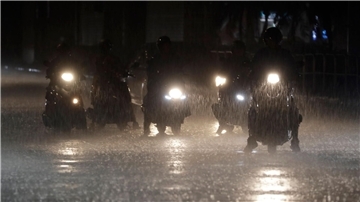 Rollerfahrer stehen bei heftigem Regen an einer Kreuzung in Taipeh.