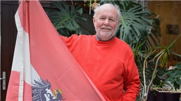 Ein Mann hält die österreichische Flagge hoch. 