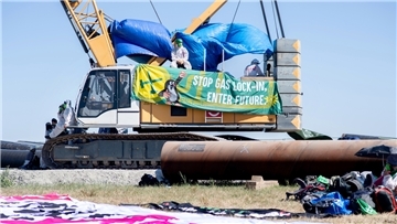 Ein Transparent mit der Aufschrift „Stop Gas Lock-In, Enter Future.“ hängt an einem Kran auf der Baustelle für die geplante Gaspipeline am Jade-Weser-Port.