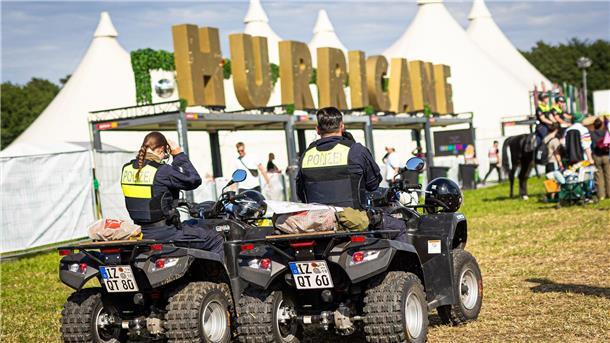 Zwei Personen auf Quads vor weißen Pagodenzelten und dem Schriftzug "Hurricane".