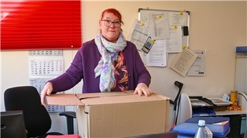 Eine Frau in einem Büro, die einen Karton packt. 