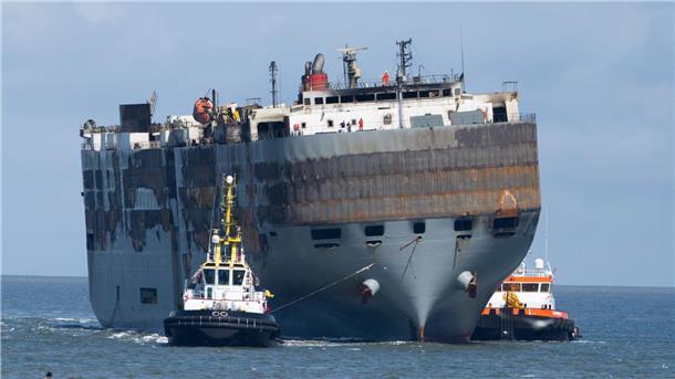 Nach Großfeuer: Beschädigter Frachter im sicheren Hafen Schlepper ziehen den Frachter in den Hafen.