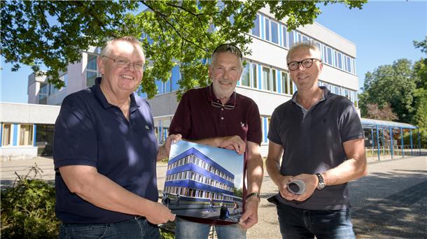 Drei Vertreter der Stadt Bremerhaven - Kämmerer torsten Neuhoff, Sportausschuss-Sprecher Detlef Müller und Holger Schneeberg von Seestadt-Immobilien - stehen vor der alten Fassade der Schule am Leher Markt und zeigen die Zeichnung, wie die neue blaue Energiespar-Fassade demnächst aussehen wird.