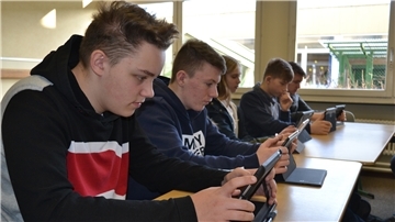 Schüler sitzen mit Tablets im Klassenraum.