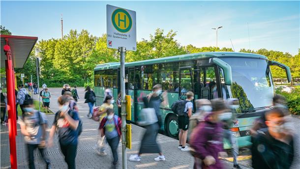 Schülerinnen und Schüler in einer verwischten Optik vor einem Schulbus am Schulzentrum in Schiffdorf. 
