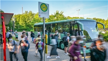 Schülerinnen und Schüler in einer verwischten Optik vor einem Schulbus am Schulzentrum in Schiffdorf. 