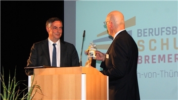 Schulleiter Lars Leminski (rechts) überreichte Festredner David McAllister einen Kaffeebecher, auf dem noch das "gelbe" Schulgebäude abgebildet ist.