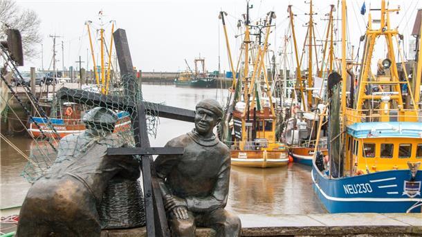 WWF: Fischerei hat sich bei Meeresschutz zu wenig bewegt Schwarze Holzkreuze lehnen an der Bronezeskulptur „Alt- und Jungfischer“ im Hafen in Neuharlingersiel. Das Fischen mit Grundschleppnetzen steht in der Kritik.