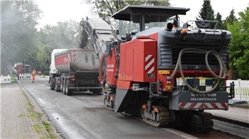 Schweres Gerät ist im Einsatz auf der Landesstraße in Rhadereistedt: Die Asphaltfräse befüllt einen Sattelzug.