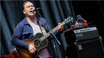 Der Musiker Thees Uhlmann steht auf der Bühne und spielt Gitarre.
