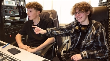 Eine junge Frau und ein Junge sitzen in einem Radio-Studio. 