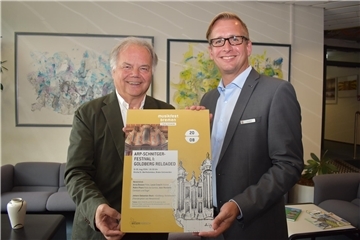 Zwei Männer lächeln und halten ein Plakat in der Hand