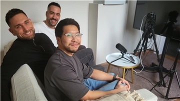 Drei Männer sitzen auf einem Sofa. Vor ihnen ist ein Bildschirm, eine Kamera und ein Mikro aufgebaut.  Sie sind Mitglieder des Vereins Ethic Train, der jungen Menschen Selbstvertrauen geben möchte.