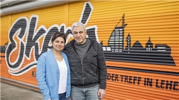 Ein Mann und eine Frau stehen vor einem Kiosk.