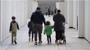 Eine Familie mit vier Kindern geht durch eine Halle.